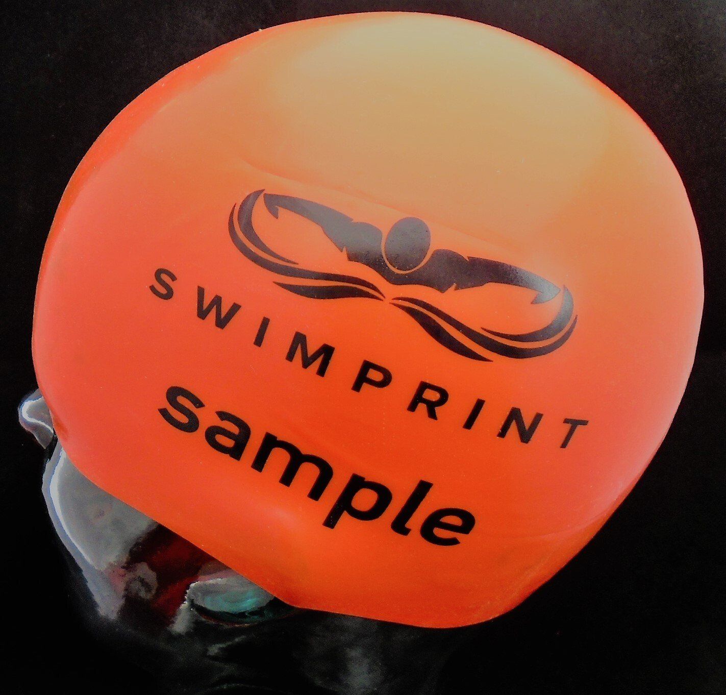 An orange swim cap that says swimprint sample on it