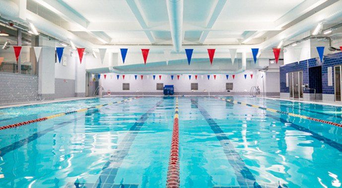 A large indoor swimming pool with flags hanging from the ceiling.