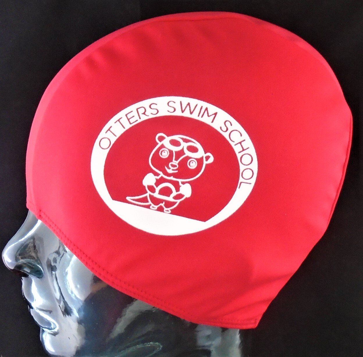 A red swim cap that says otters swim school