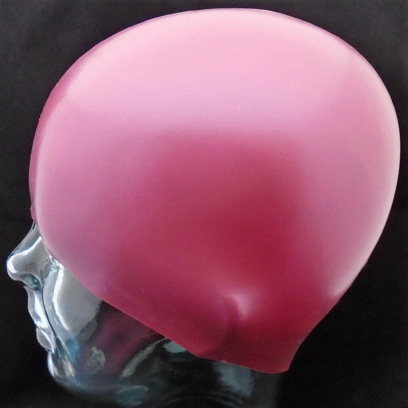 A pink swim cap is on a mannequin head