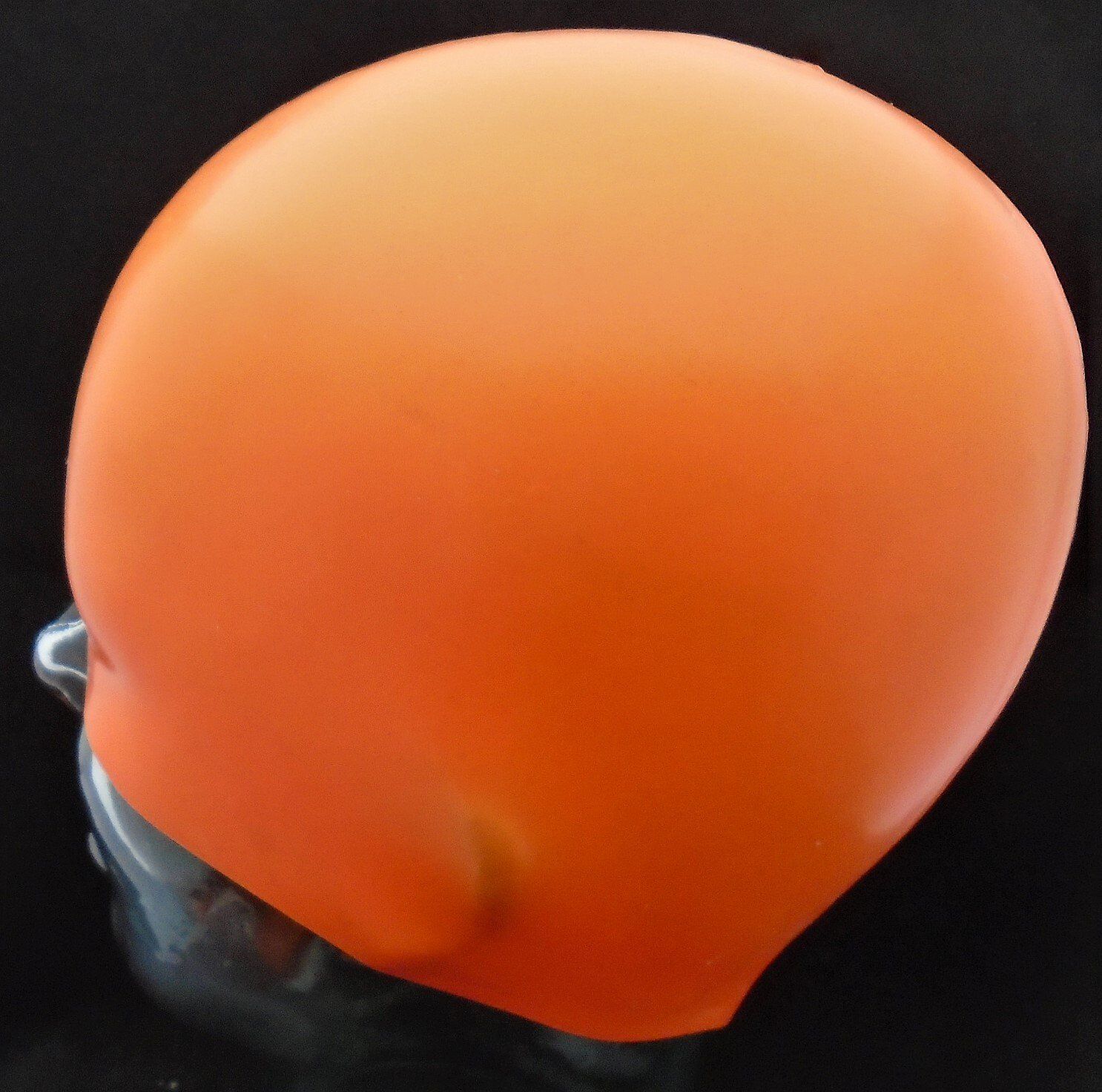 An orange swimming cap is on a mannequin head