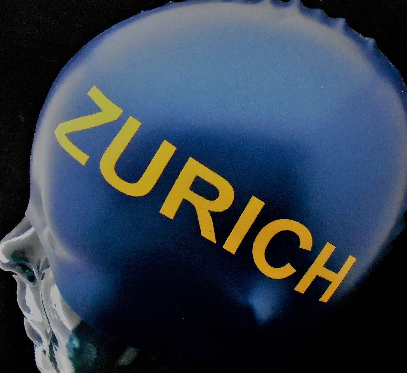A blue bottle cap with the word zurich on it