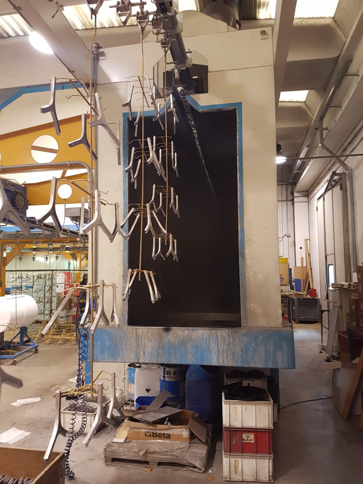 Macchinario industriale in un'officina con cavi penzolanti e un grande pannello nero.