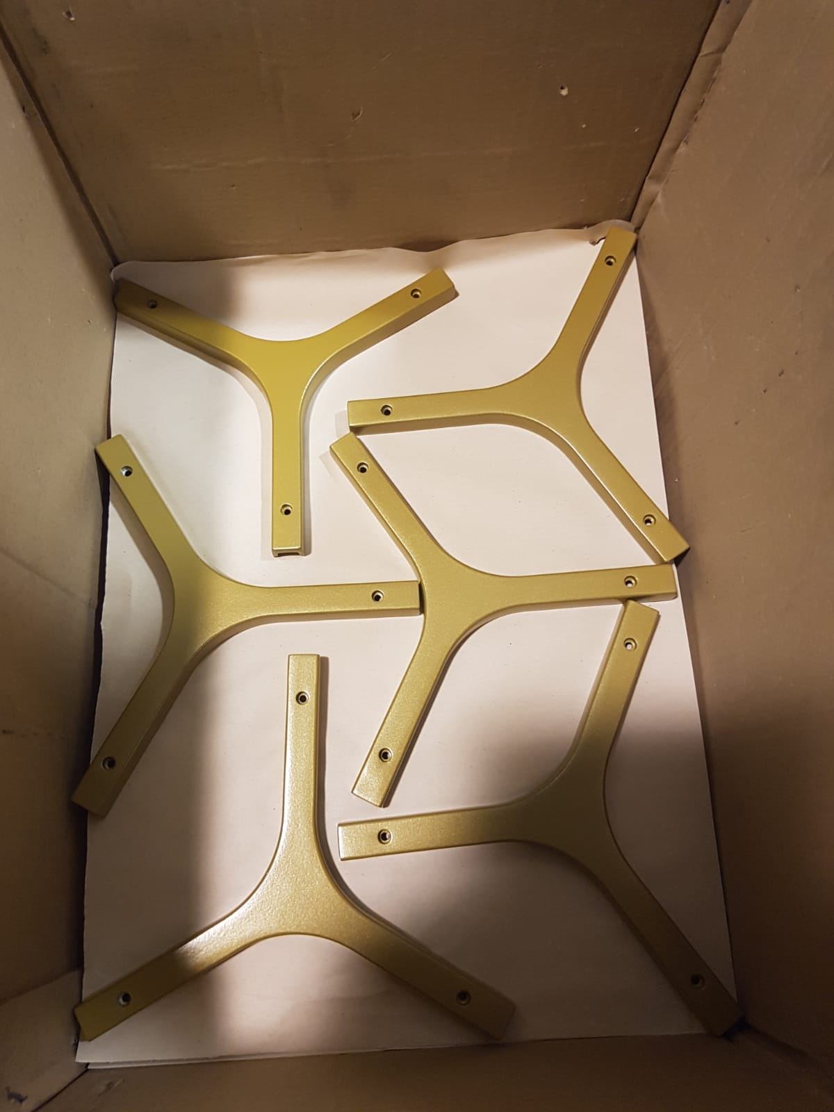 Staffe metalliche gialle disposte all'interno di una scatola di cartone, viste dall'alto.