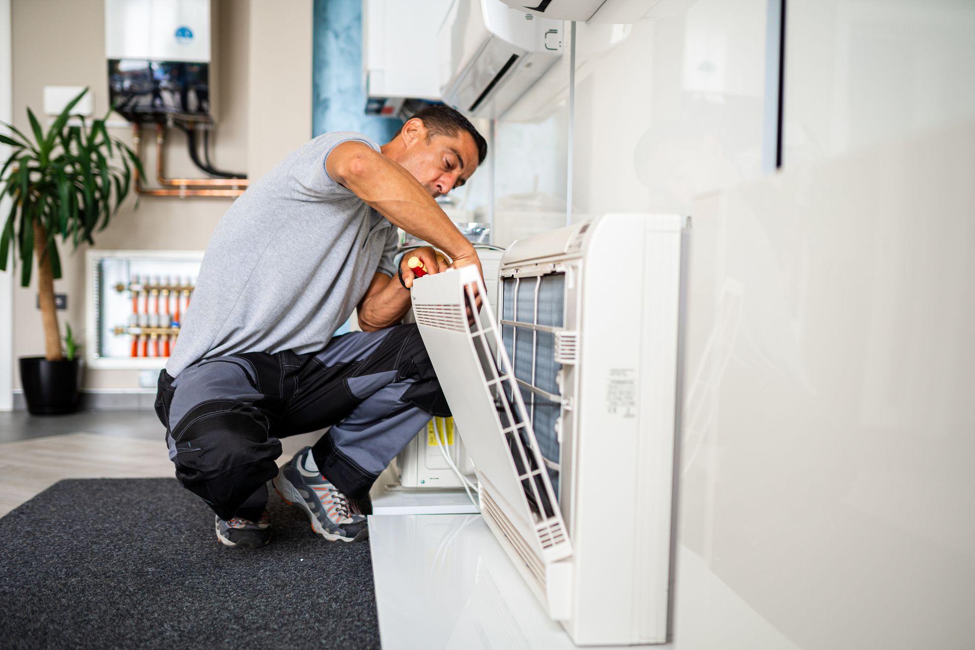 A man is working on an air conditioner in a living room.