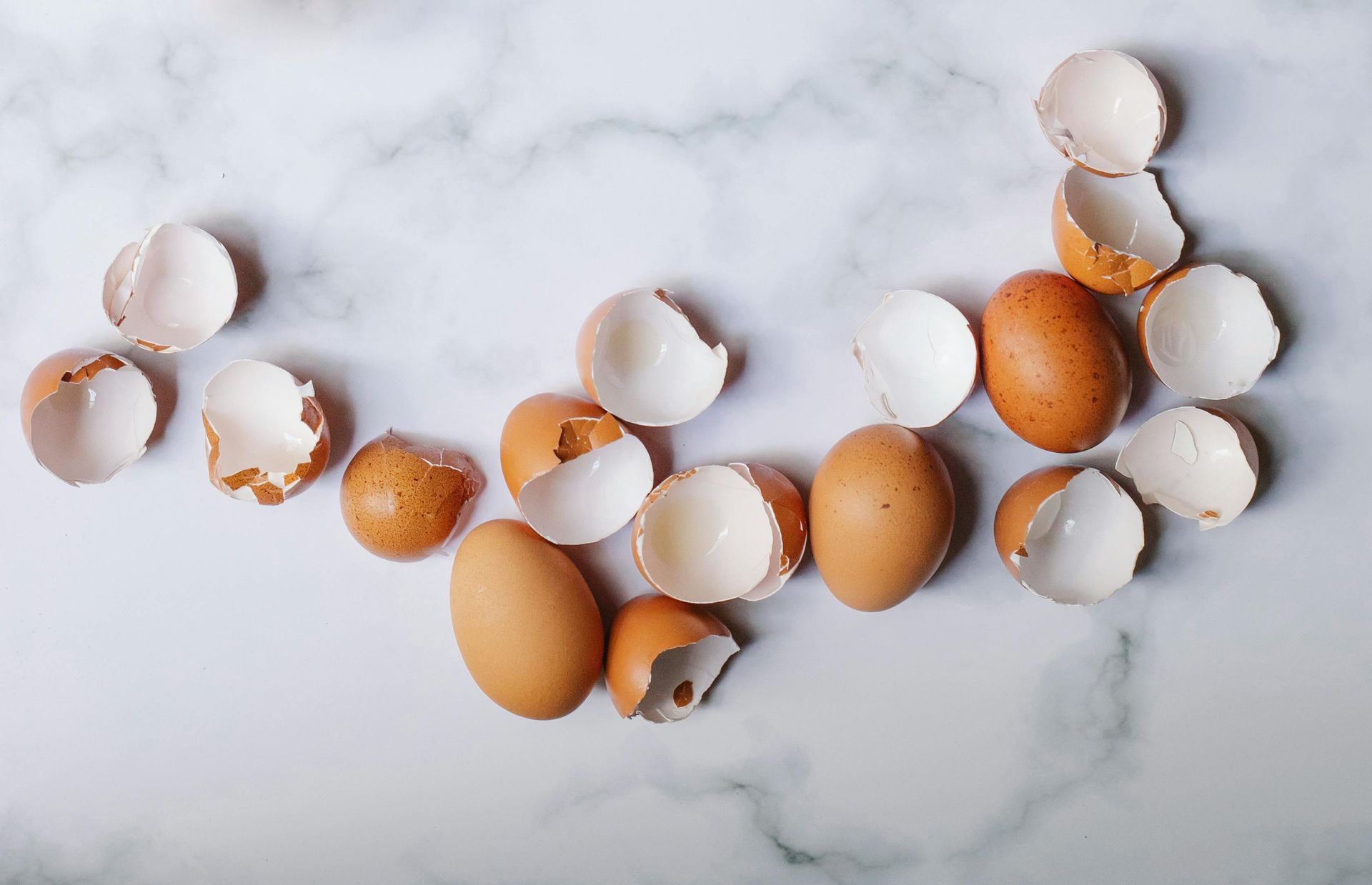 Brown eggs and shell fragments on a white marble surface.