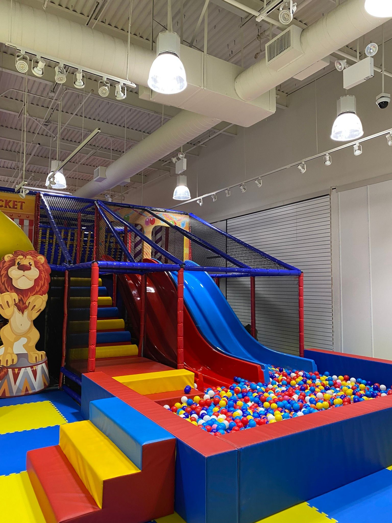 A children 's playground with a slide , stairs , and a ball pit.