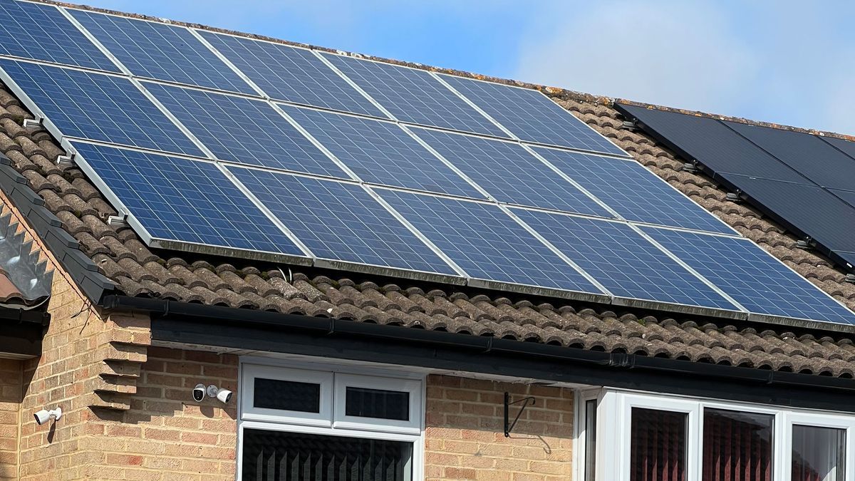 There are many solar panels on the roof of a house.