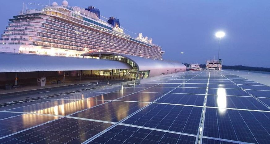 A large cruise ship is behind a row of solar panels