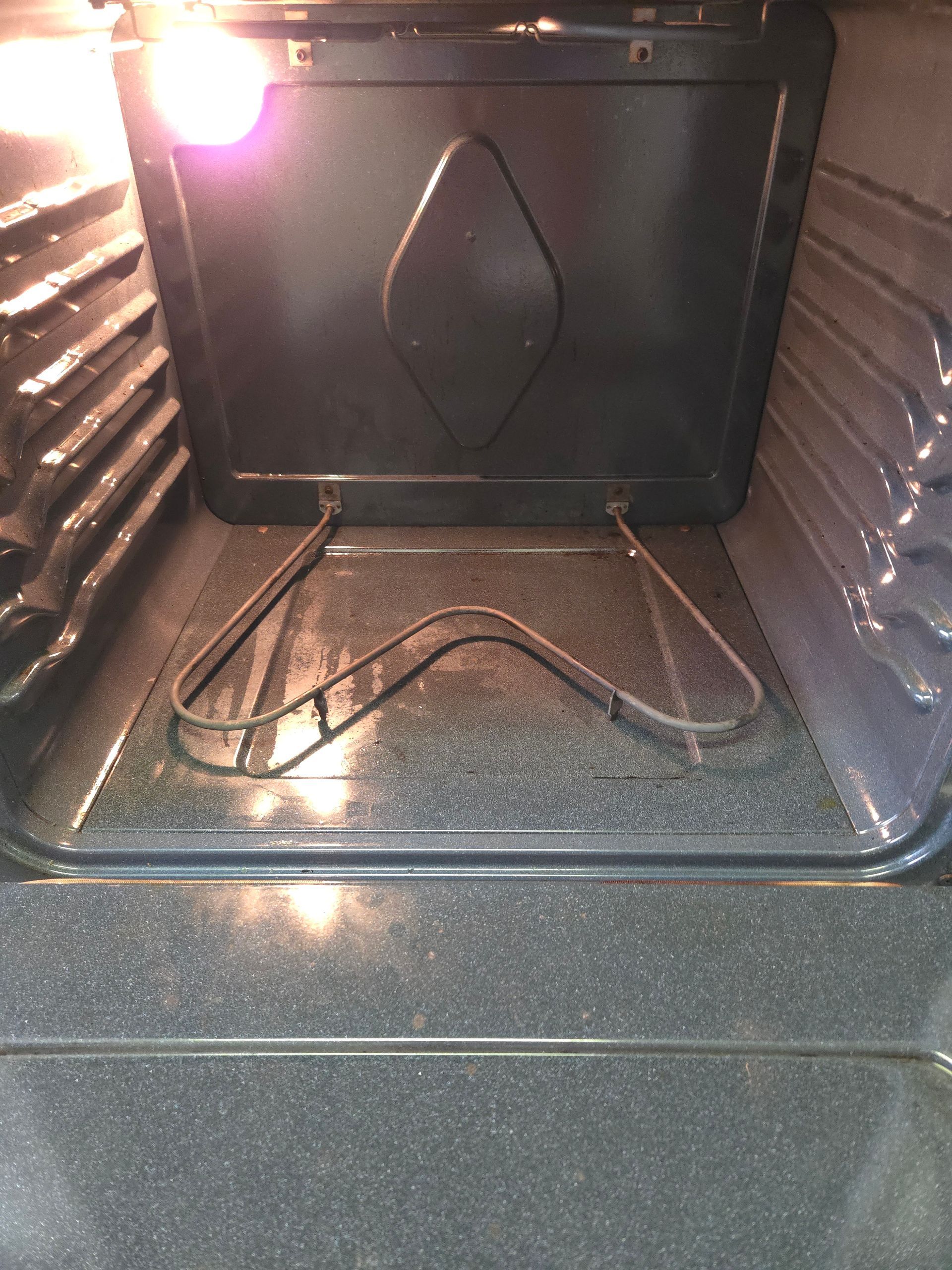 Inside an oven with a heating element at the bottom. The oven is empty with a light on, showing the interior.
