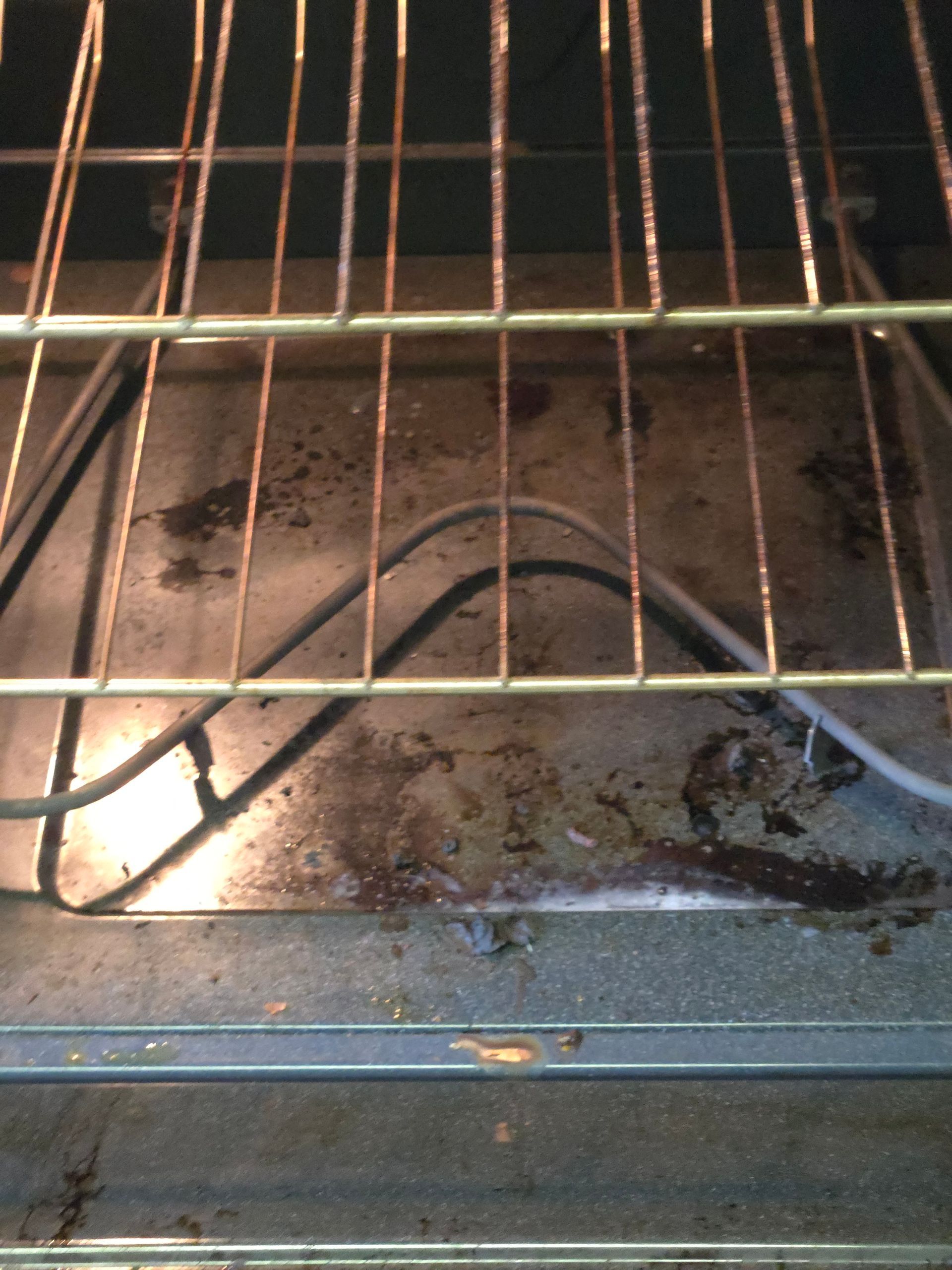 Dirty oven interior with a wire rack and visible food residue.