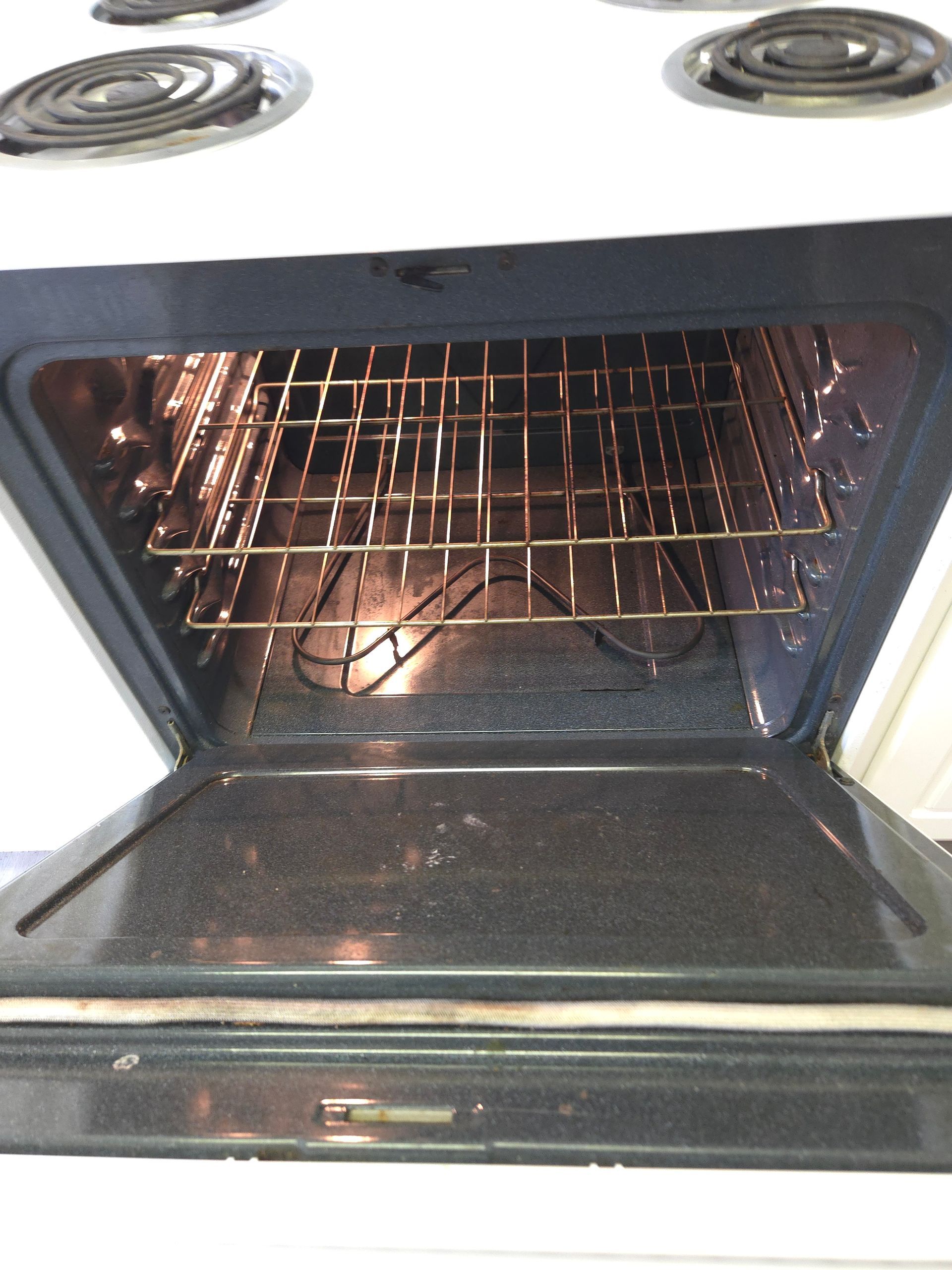Open oven showing interior with racks and heating element, with a partially open door.
