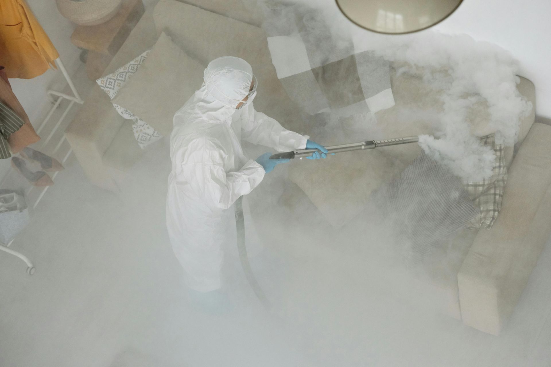 A man in a protective suit is spraying a room with a sprayer.