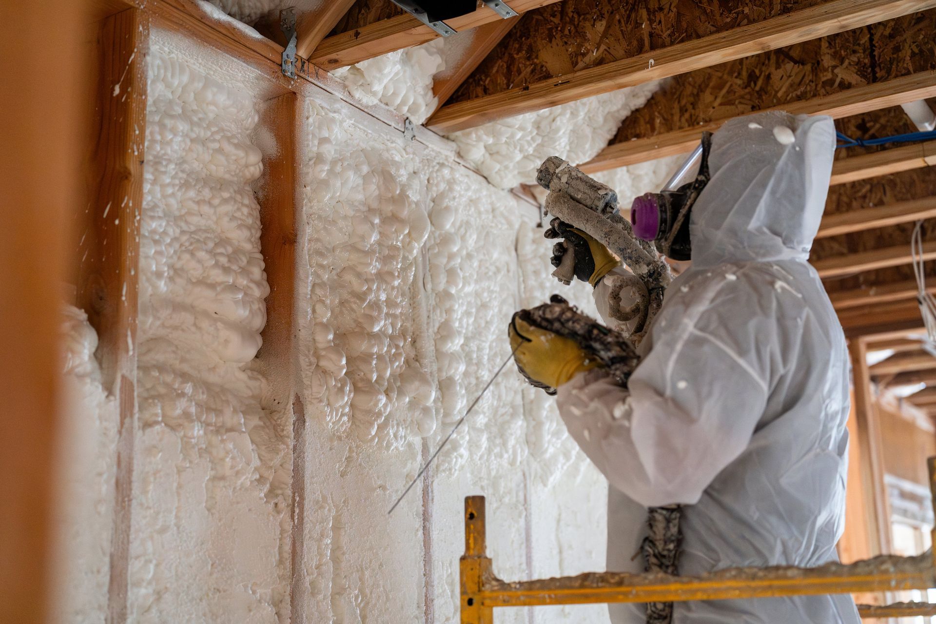 A man working on house insulation with open-cell foam.