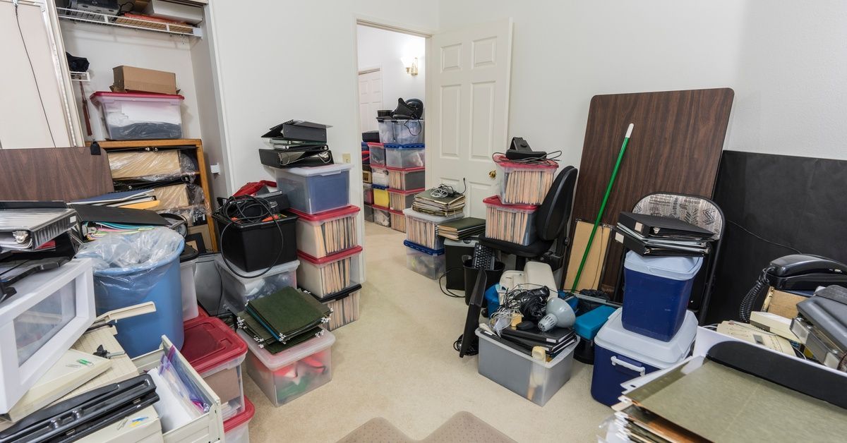 A cluttered storage room, hall, and closet contain plastic bins, stacked papers, binders, and scatte