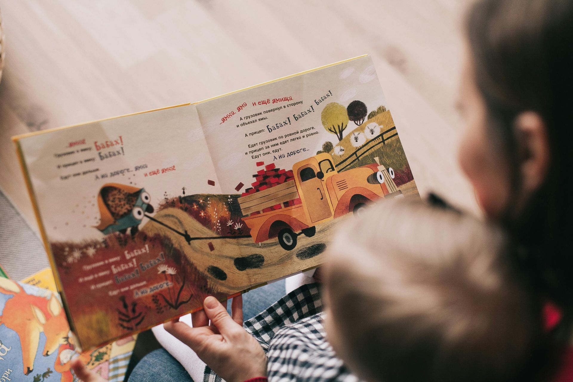 A woman is reading a book to a baby.