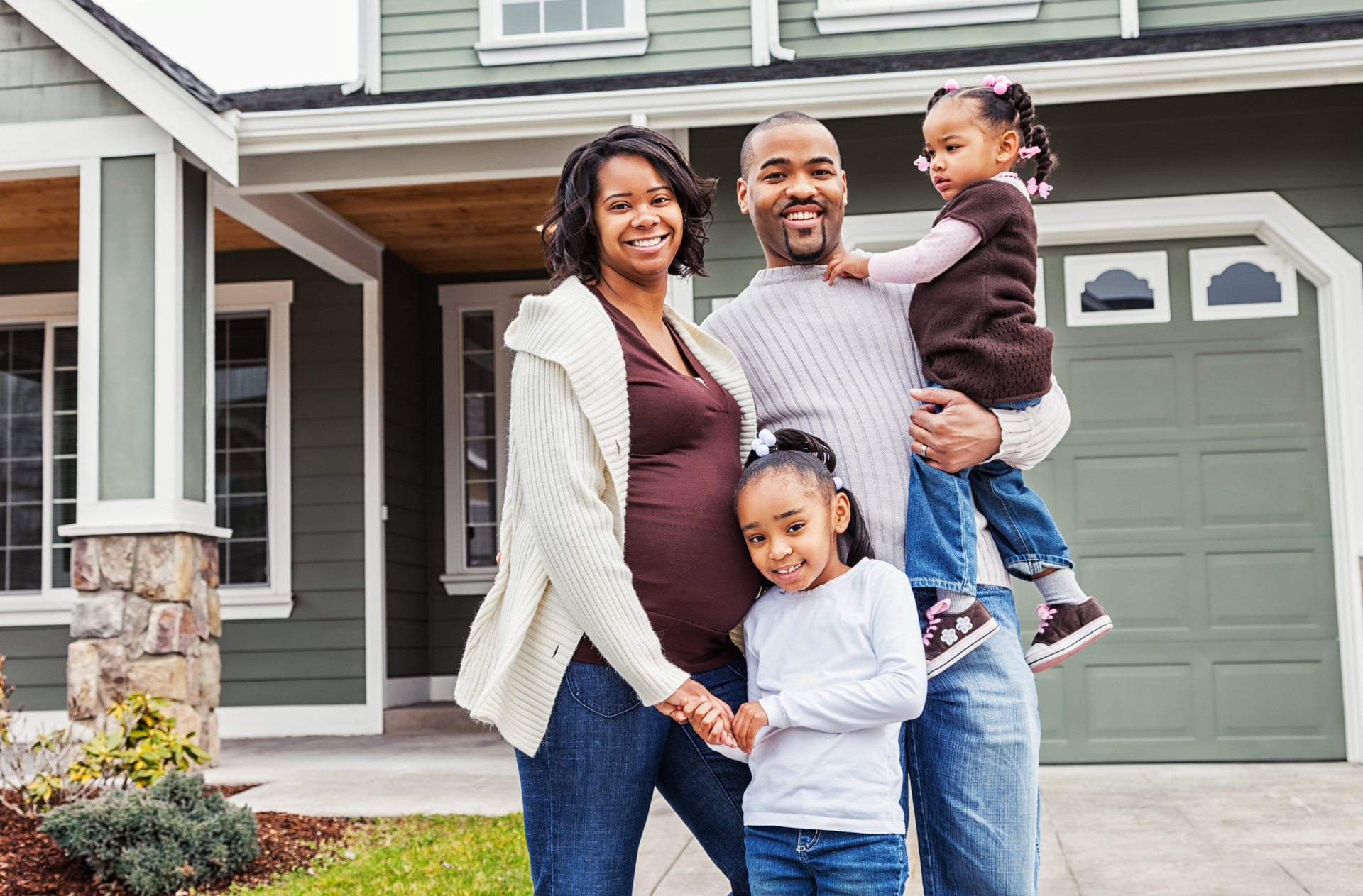 A family of four is standing in front of a luxury rental managed by TN Livin' Property Solutions