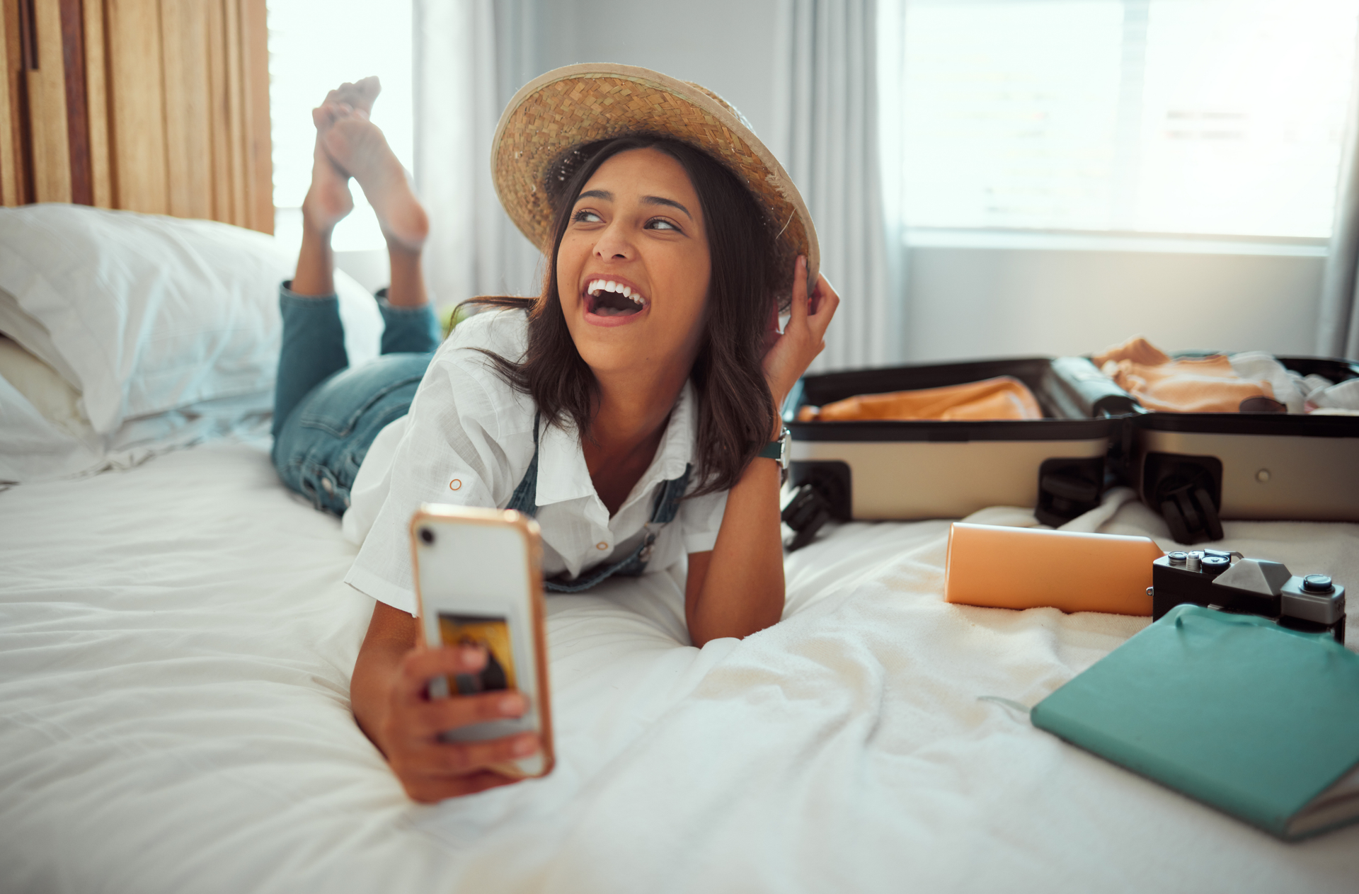 A woman is laying on a bed texting and laughing after arriving at her new modern Airbnb Rental