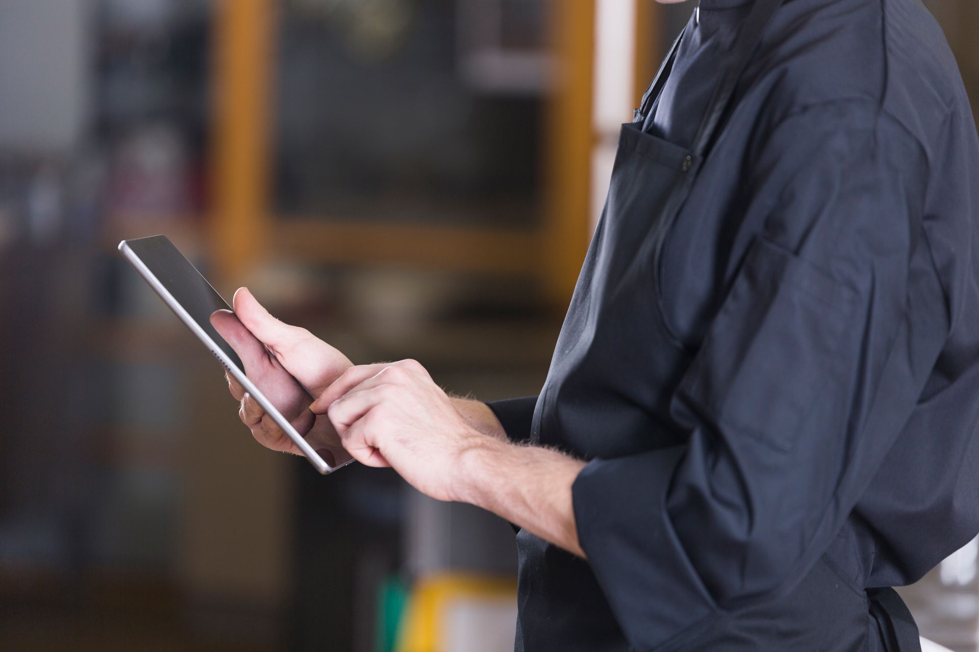 Um homem de avental está usando um tablet.