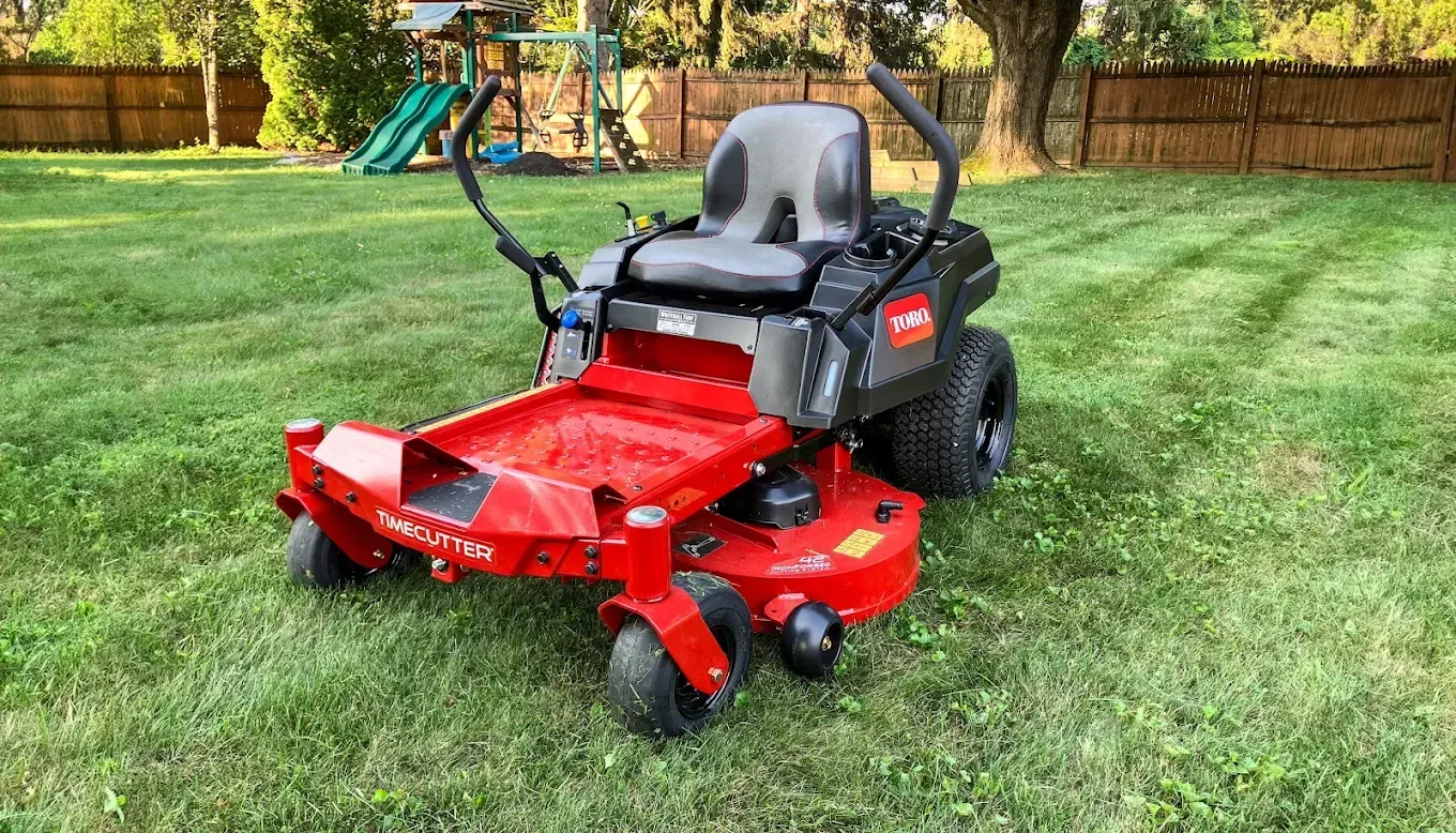 Red Toro zero-turn riding lawn mower on a green lawn.