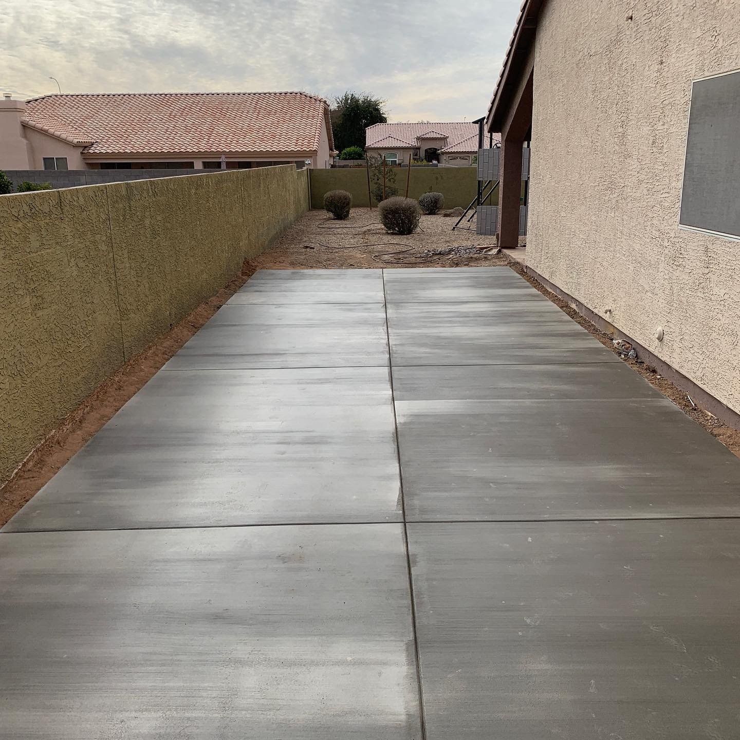 A concrete driveway with a house in the background