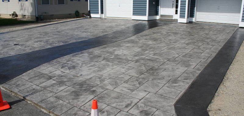 A concrete driveway is being painted in front of a house.
