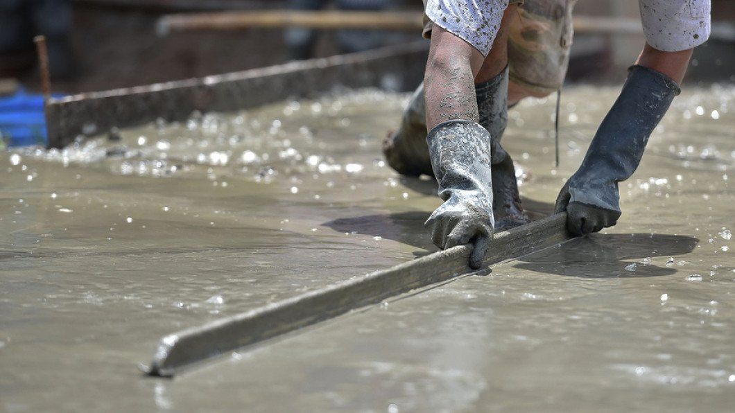 A person is working on a concrete floor with a trowel.