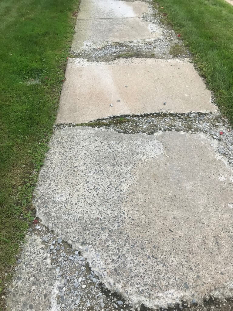A concrete sidewalk with grass on the side of it.