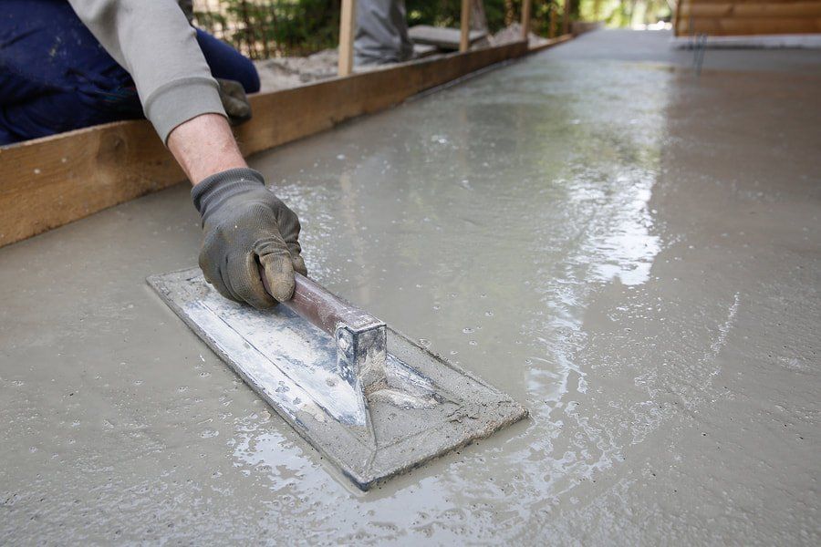 A man is using a trowel to level a concrete floor.