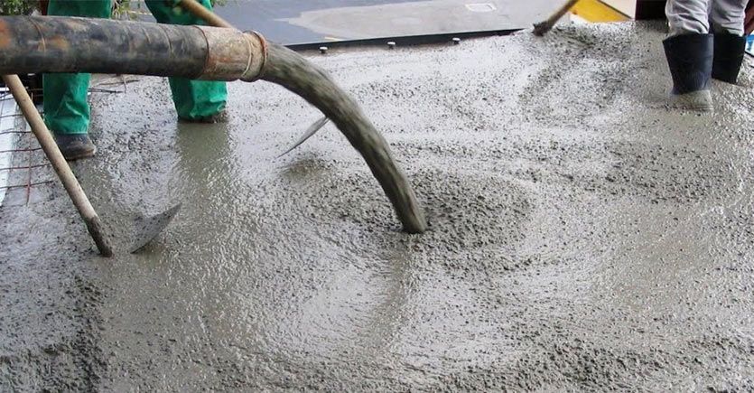 A hose is being used to pour concrete into a concrete floor