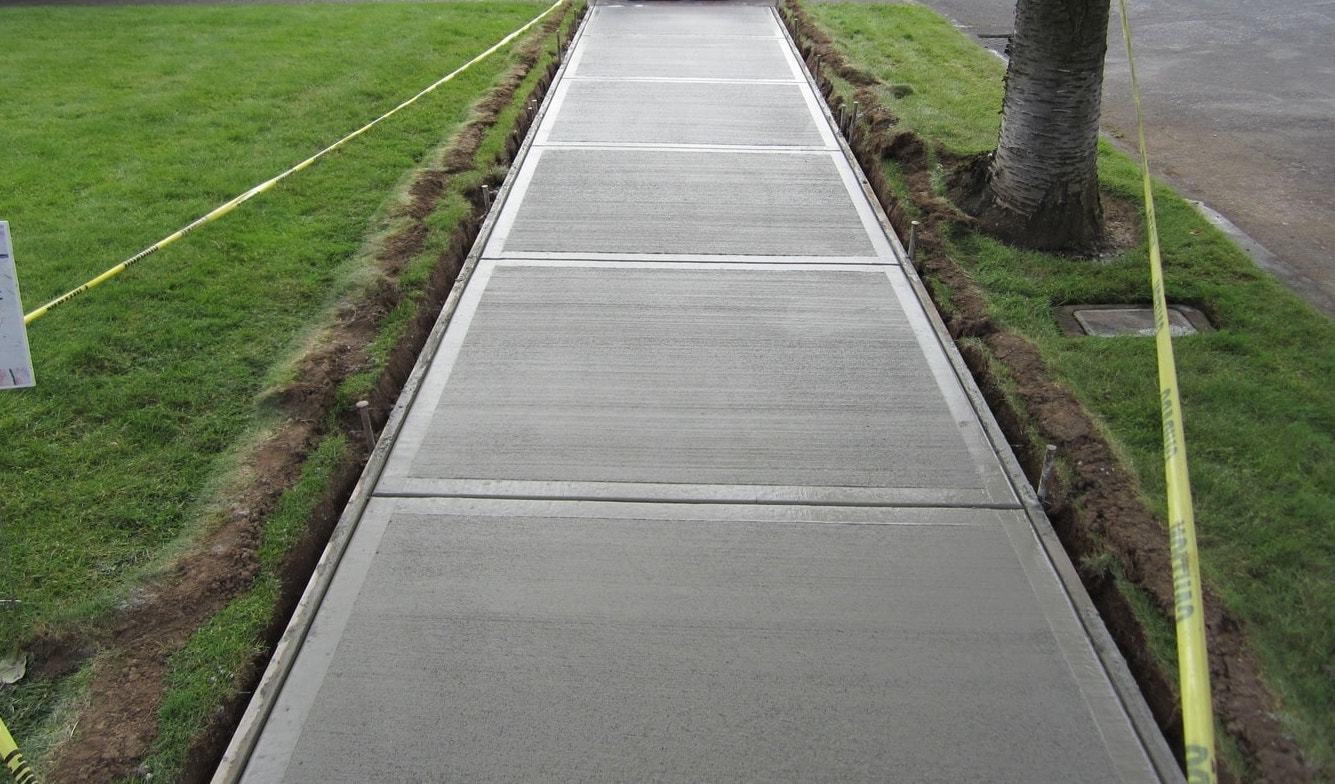 A concrete sidewalk is being built next to a grassy field.