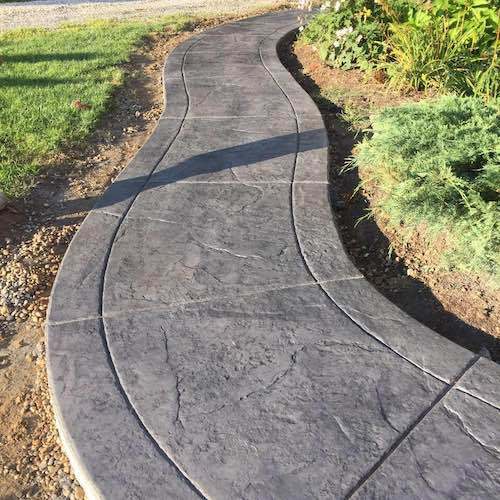A curved concrete walkway leading to a garden.