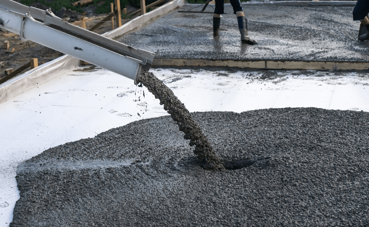 A person is pouring concrete into a pile of gravel.