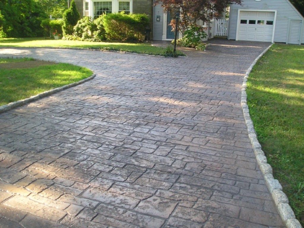 A brick driveway leading to a house with a white garage door