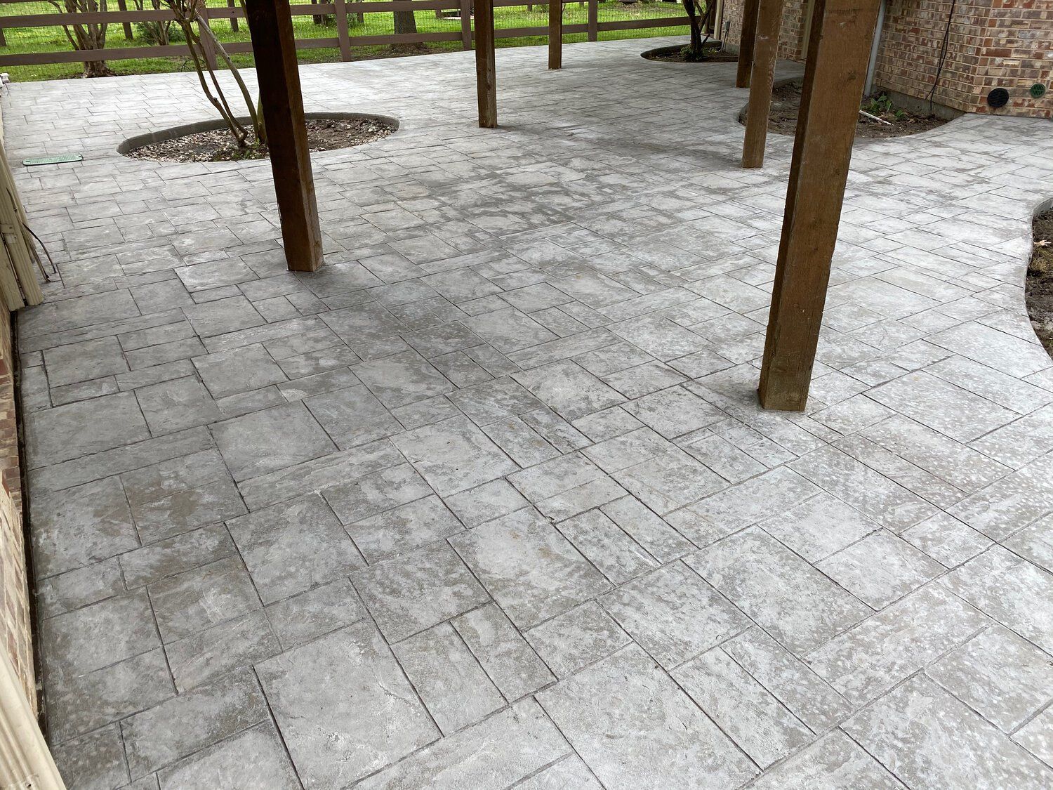 A patio with a pergola and a fence in the background.