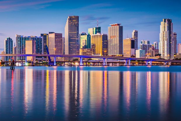 Miami city skyline at sunset with colorful lights reflecting on the water