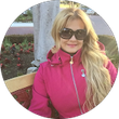 Portrait of Aleimy Acosta wearing sunglasses and a pink jacket outdoors