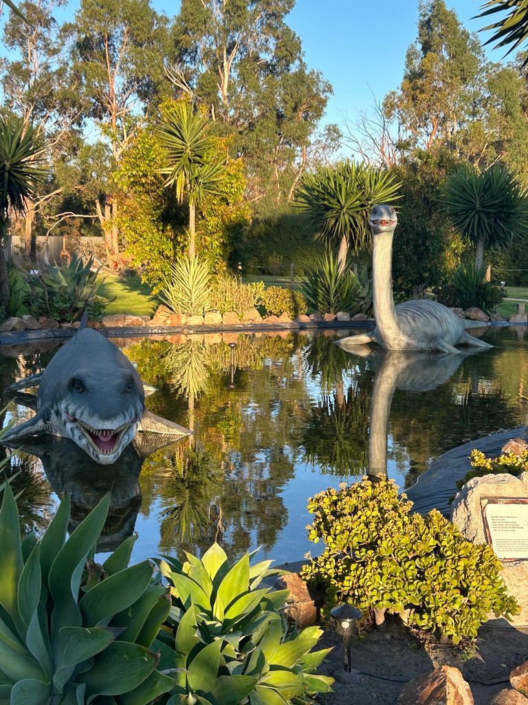 A statue of a dinosaur is sitting in a pond.