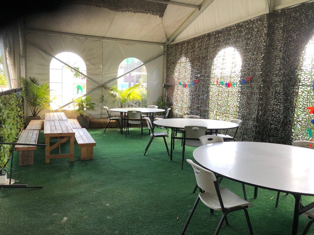 A tent with tables and chairs inside of it.