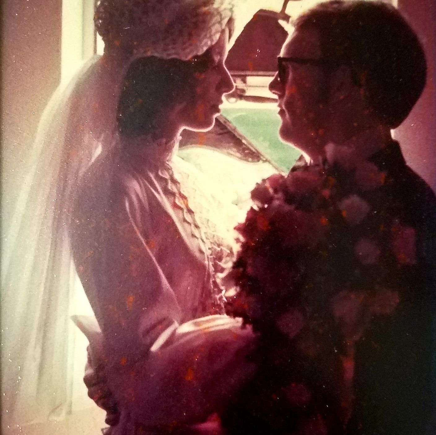 Woman with long dark hair smiles broadly, wearing a striped shirt against a white backdrop.