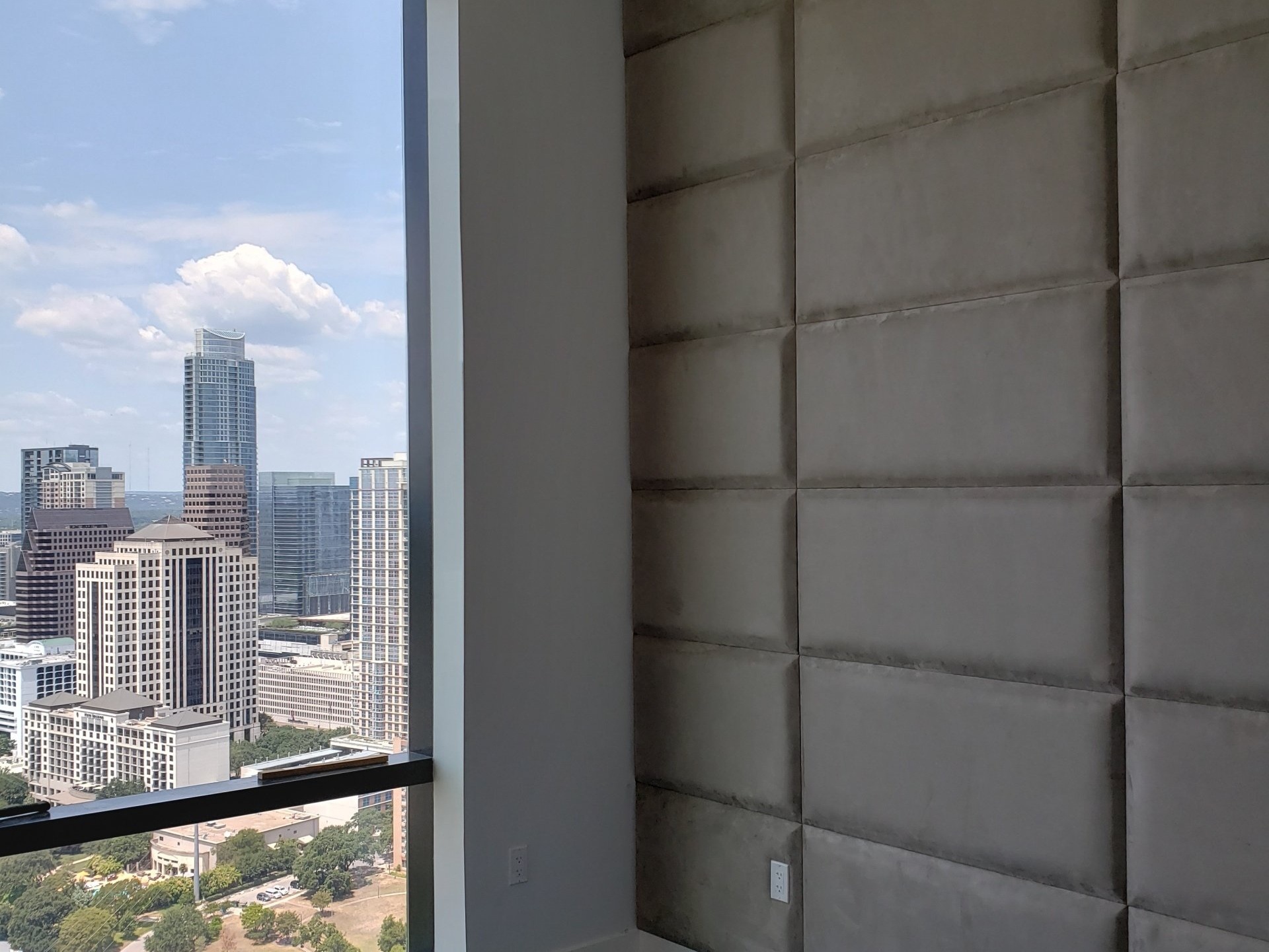A bedroom with a large window and a view of a city.