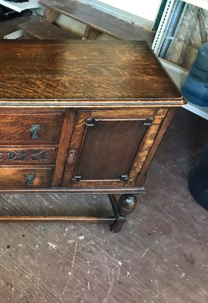A wooden table with drawers and a door is sitting on a wooden floor.