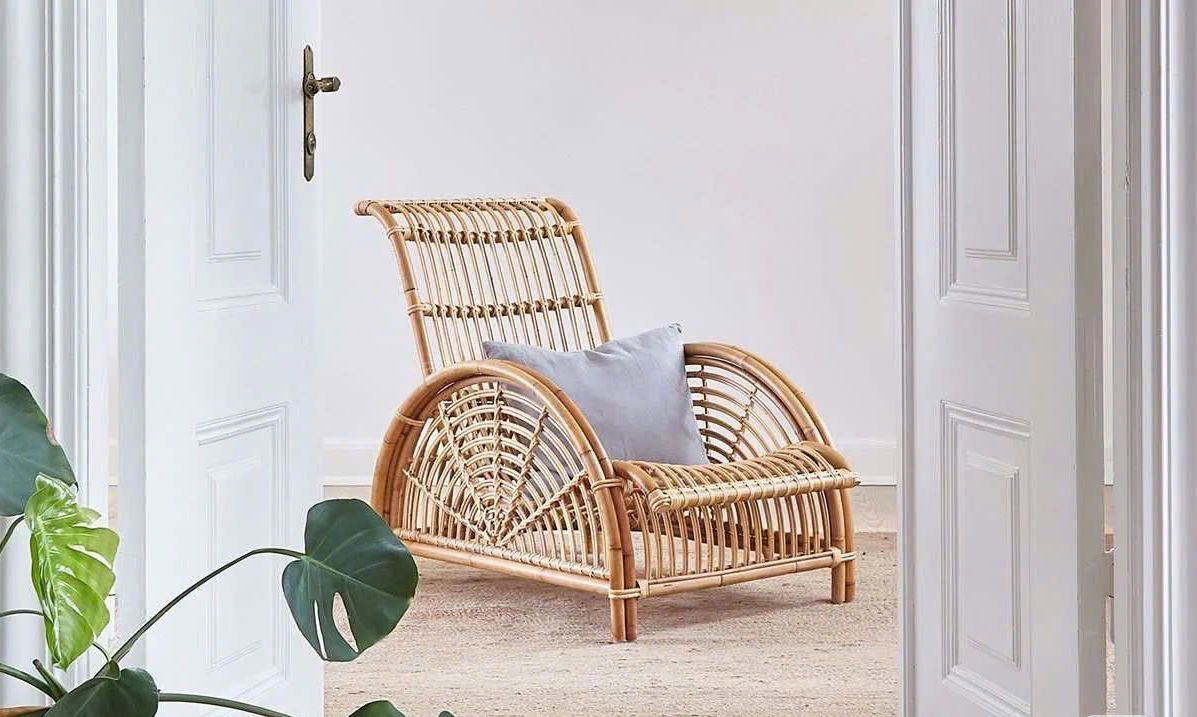 A wicker chair is sitting on a rug in a room next to a door.