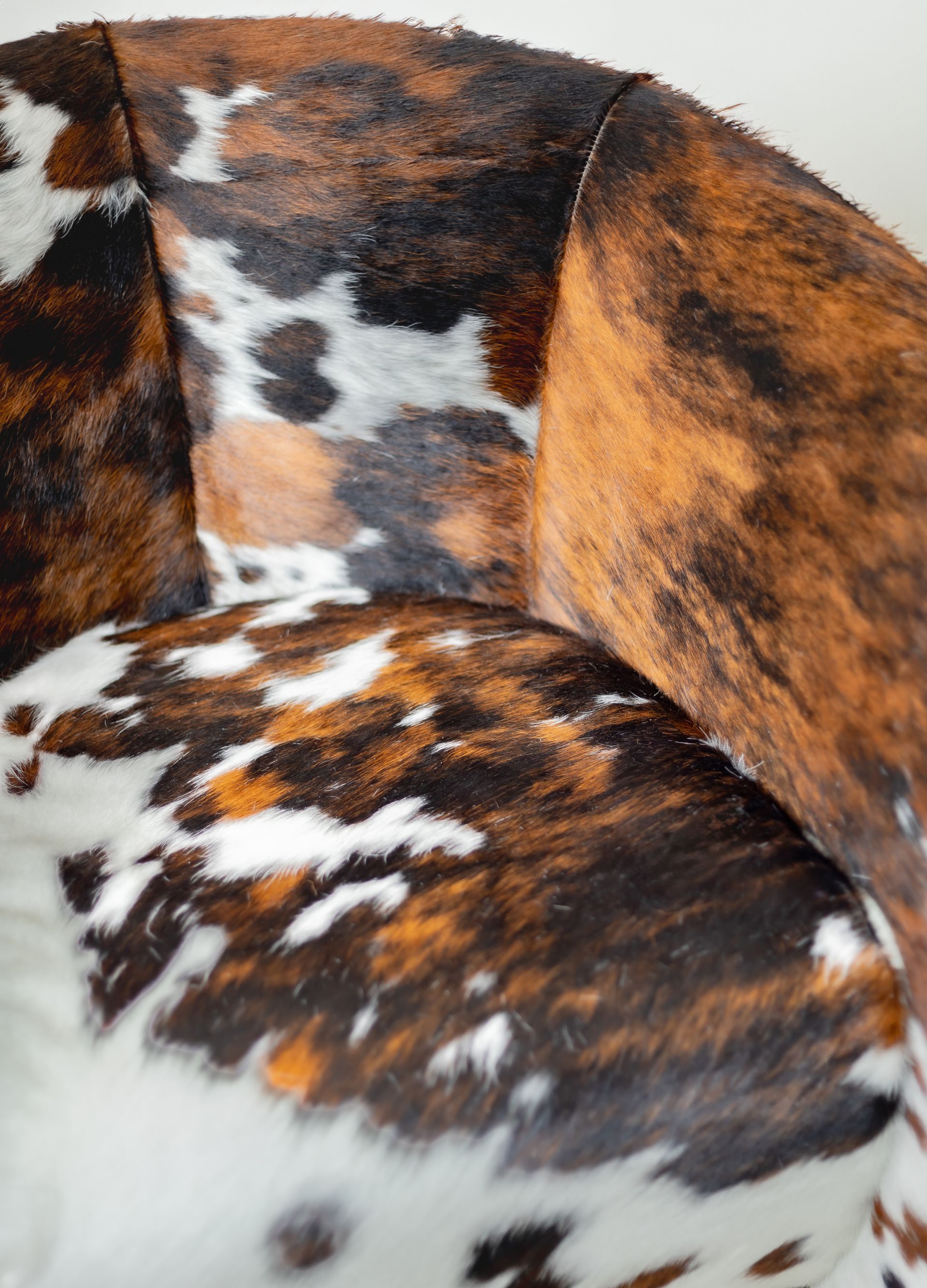 A close up of a brown and white cow print chair