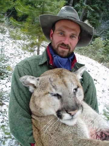 A man in a hat is holding a mountain lion