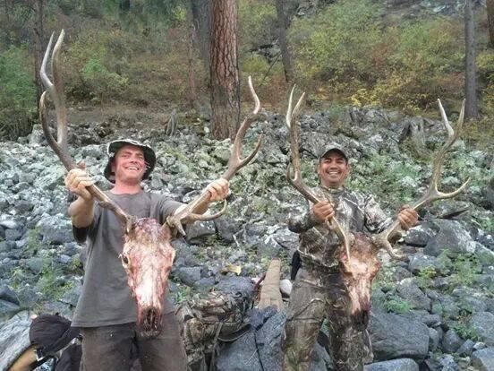 Two men are standing next to each other holding deer antlers.