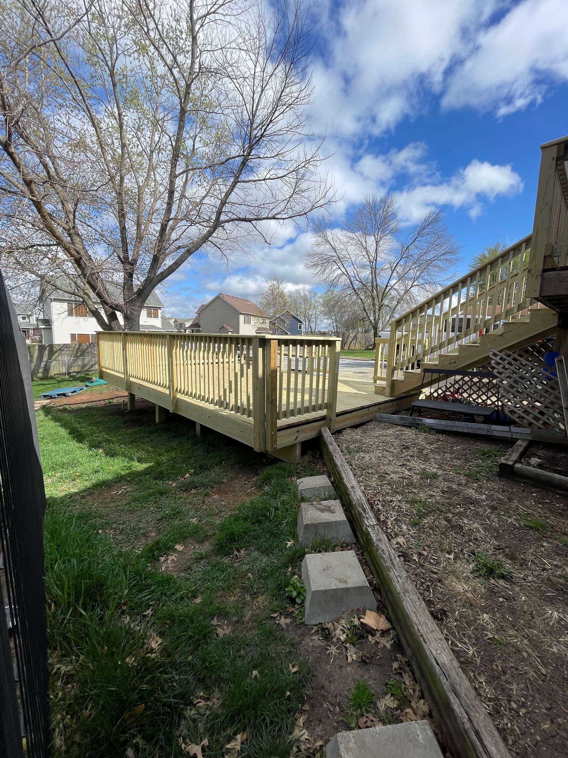 A man is working on a wooden deck in front of a house.