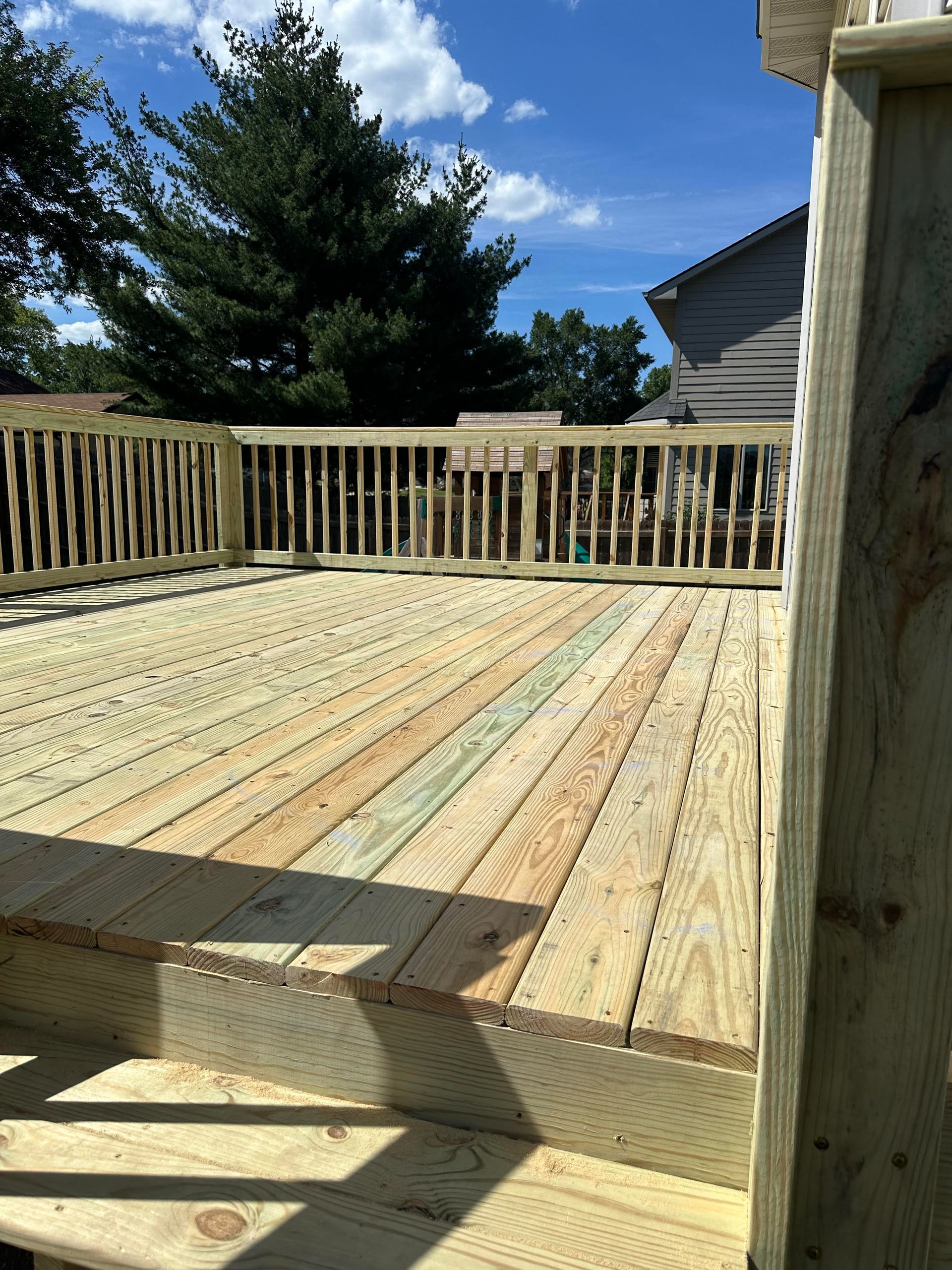 A man is working on a wooden deck in front of a house.