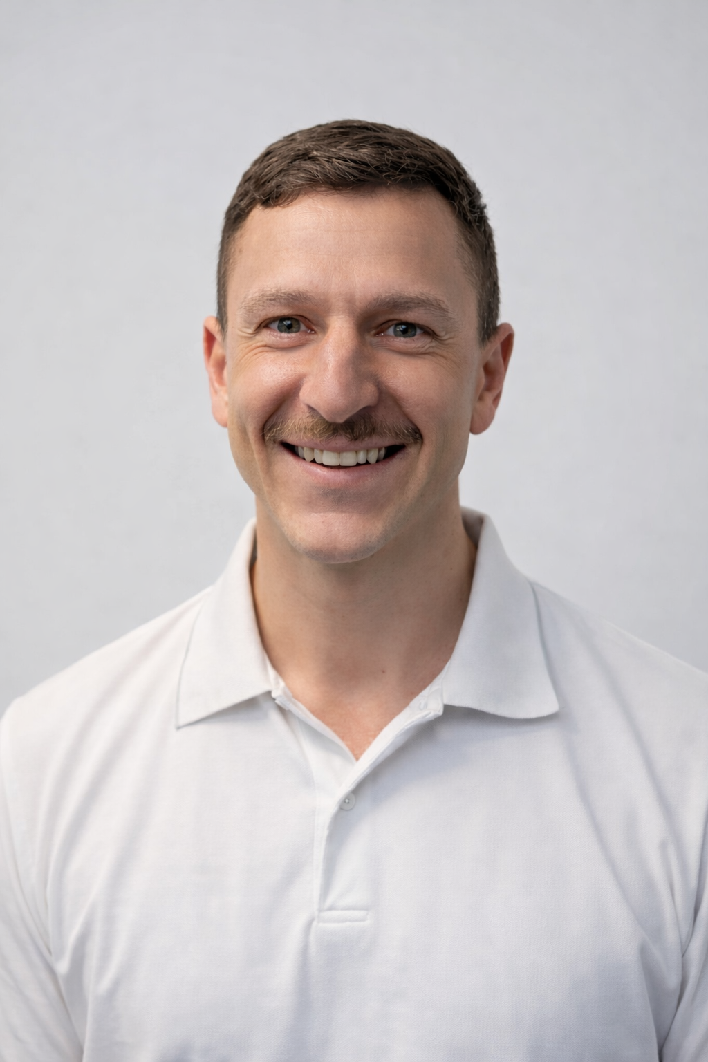 A man in a black shirt is standing in front of a barbell in a gym.