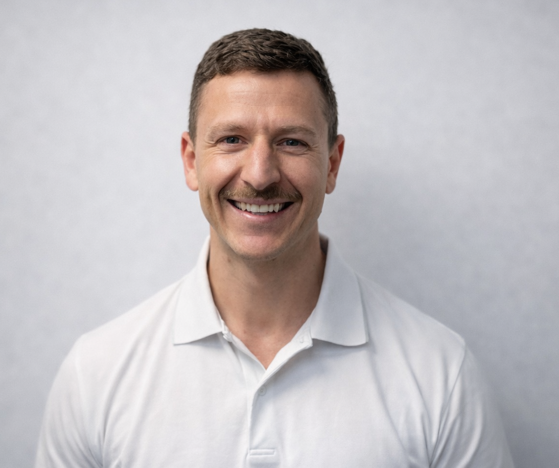 A man in a black shirt is standing in front of a barbell in a gym.